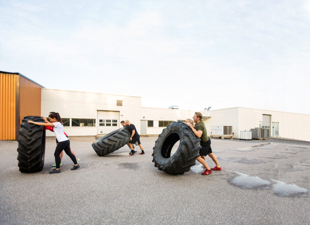 Athletes Doing Tire-Flip Exercise Outdoors coaching gogetter