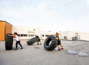 Athletes Doing Tire-Flip Exercise Outdoors coaching gogetter